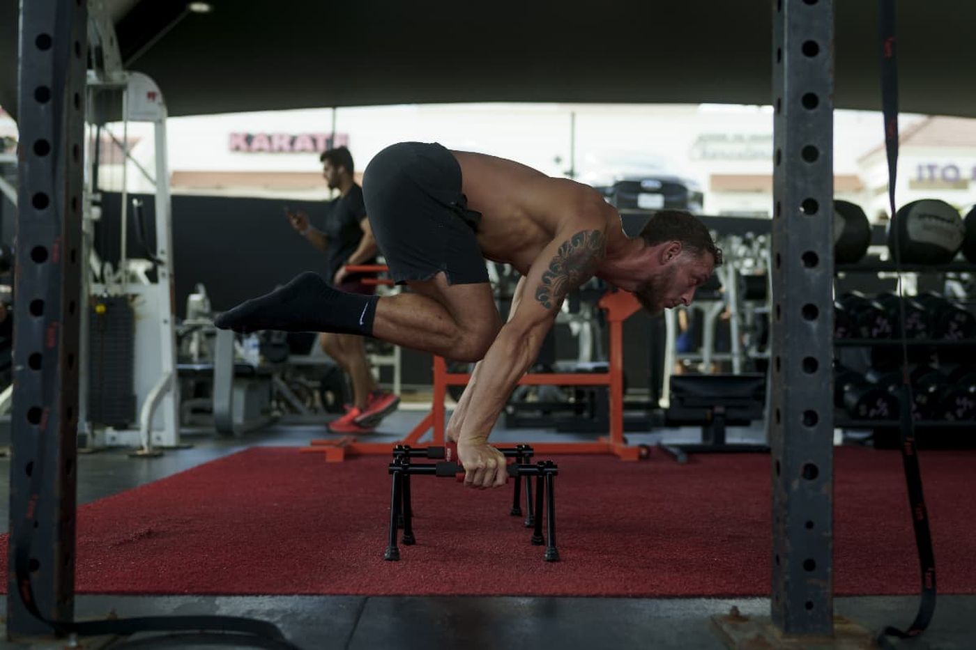 Paul holding a tuck planche on parallettes at Beast Gym