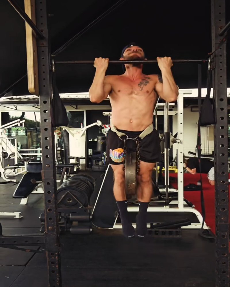Paul doing a pull-up with 100 pounds of extra weight