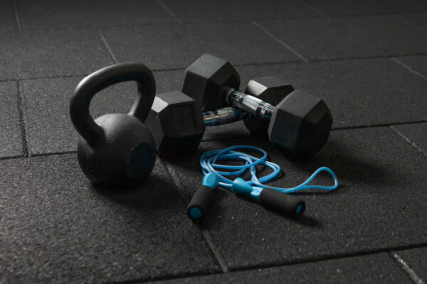 Functional training Sports equipment. Kettlebell and skipping rope, dumbbells on a dark black floor. Bodybuilding and fitness